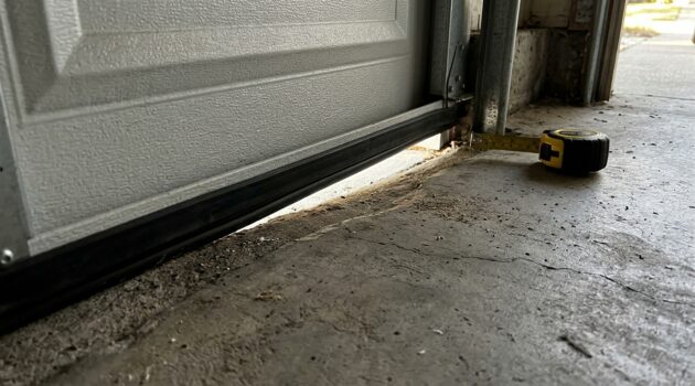 Garage door bottom gap caused by uneven concrete near the corner of a closed door